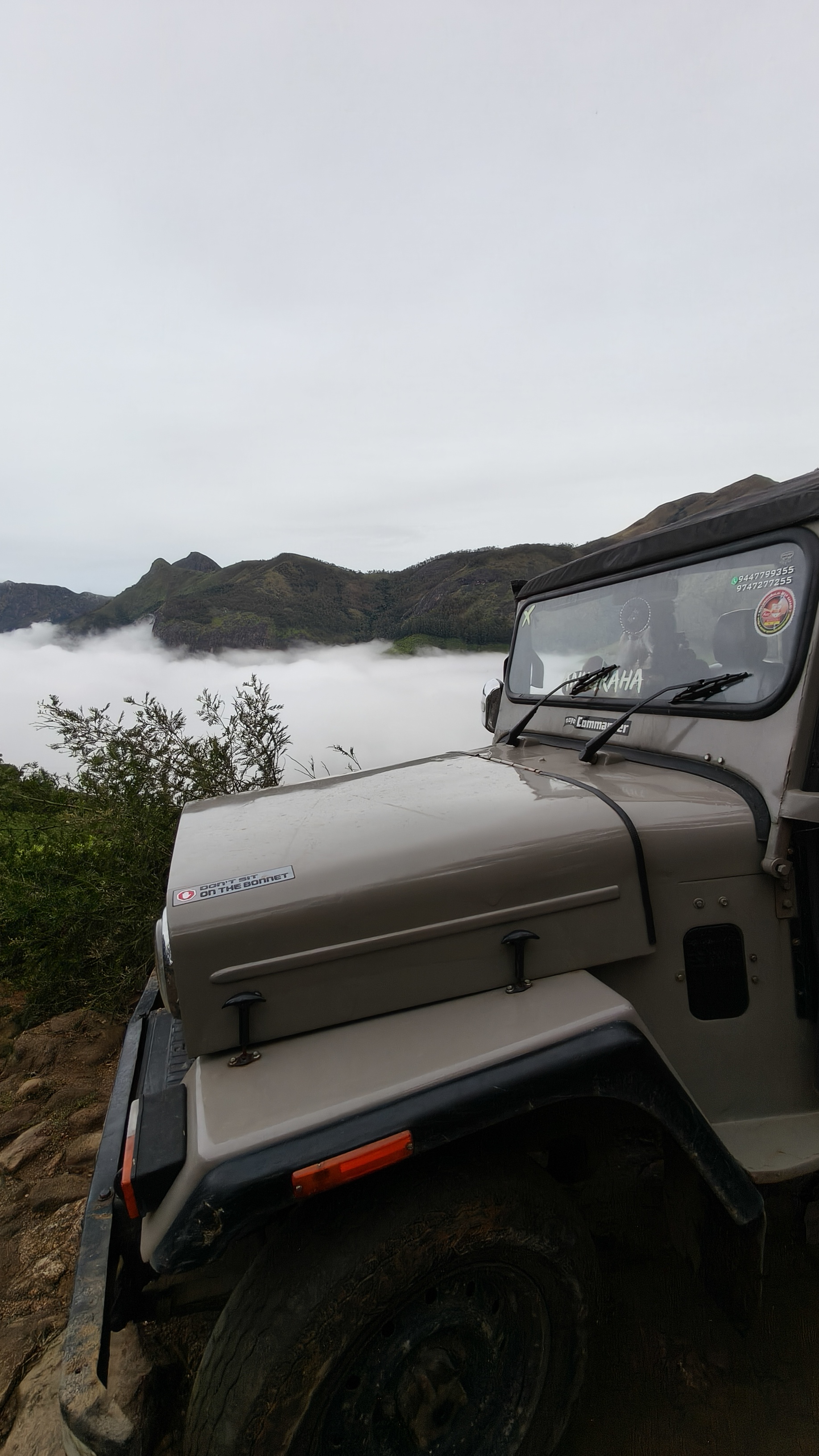 Kolukkumalai off-road jeep parked near viewpoint overlooking cloud-filled valley